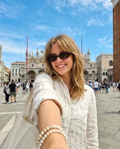 Wide-angle smartphone selfie at Piazza San Marco in Venice, radiant smile with tortoiseshell sunglasses, Byzantine basilica behind