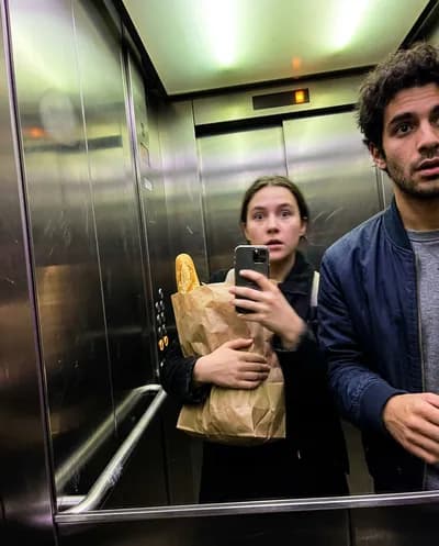 Accidental tilted elevator selfie with grocery bag and friend barely in frame, motion blur and fingerprint smudge on lens