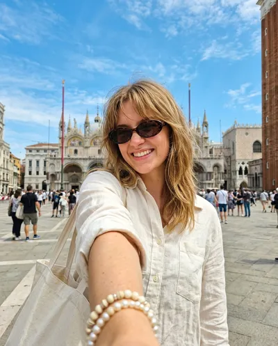 Wide-angle smartphone selfie at Piazza San Marco in Venice, radiant smile with tortoiseshell sunglasses, Byzantine basilica behind