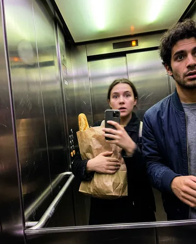 Accidental tilted elevator selfie with grocery bag and friend barely in frame, motion blur and fingerprint smudge on lens